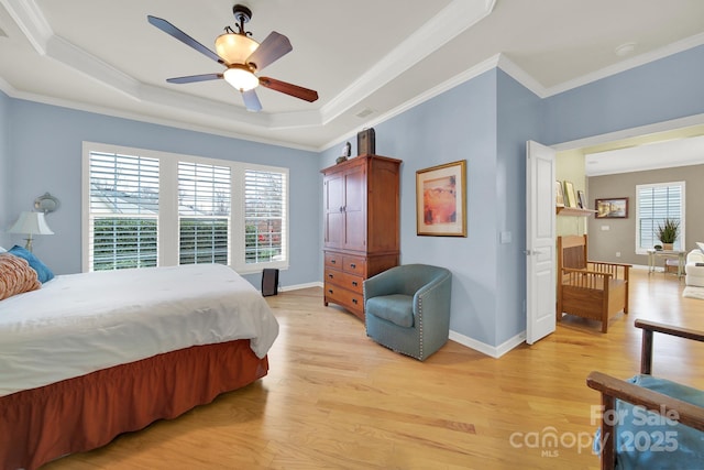 bedroom featuring a raised ceiling, ornamental molding, and light wood-type flooring