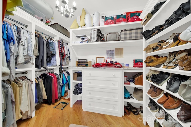 spacious closet with an inviting chandelier and light wood-type flooring