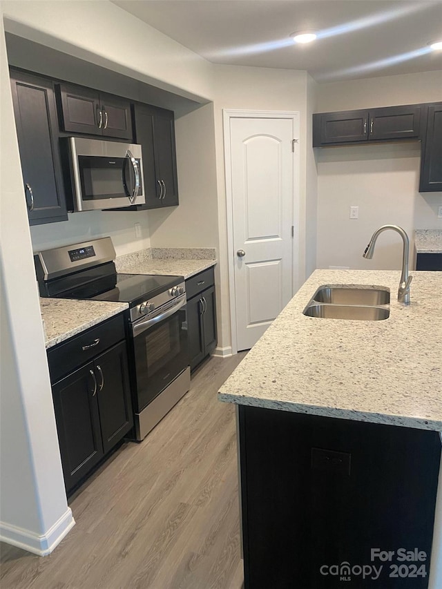 kitchen featuring light stone countertops, sink, stainless steel appliances, and light hardwood / wood-style floors