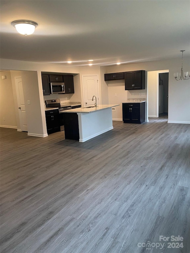 kitchen featuring hanging light fixtures, dark hardwood / wood-style floors, an island with sink, appliances with stainless steel finishes, and a chandelier