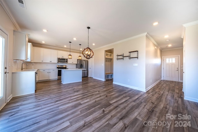 kitchen featuring dark hardwood / wood-style flooring, ornamental molding, stainless steel appliances, white cabinetry, and a kitchen island