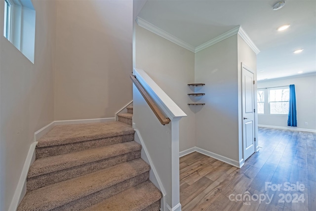 stairway with wood-type flooring and ornamental molding