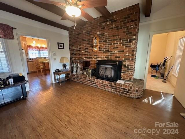 living room featuring beamed ceiling, hardwood / wood-style floors, a fireplace, and ceiling fan