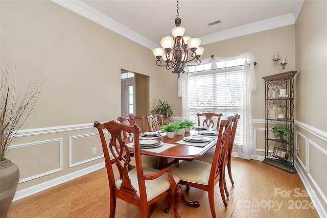 dining area featuring light hardwood / wood-style floors, crown molding, and an inviting chandelier