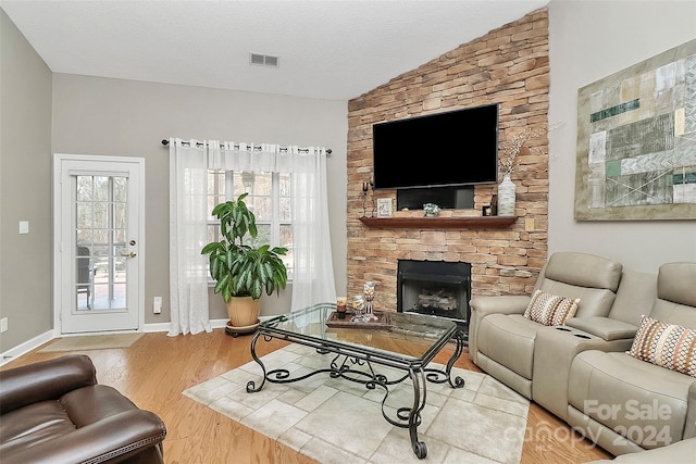 living room with a fireplace, hardwood / wood-style floors, a textured ceiling, and vaulted ceiling