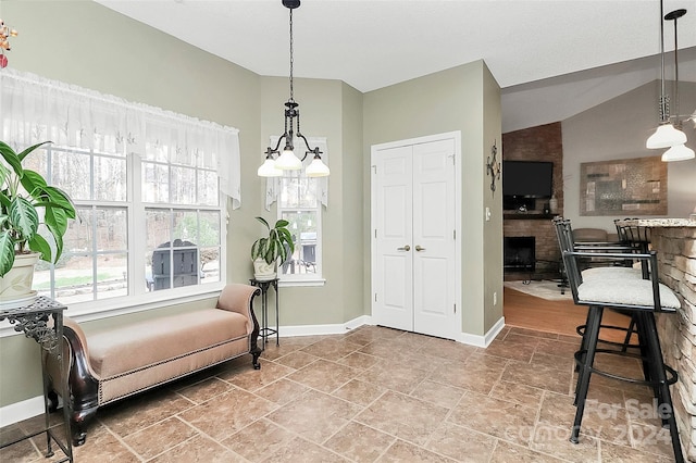 living area featuring a fireplace, vaulted ceiling, and an inviting chandelier