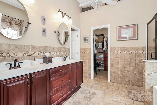 bathroom with ceiling fan, vanity, tile walls, and walk in shower