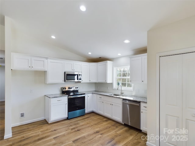 kitchen with light hardwood / wood-style floors, sink, white cabinetry, light stone countertops, and stainless steel appliances