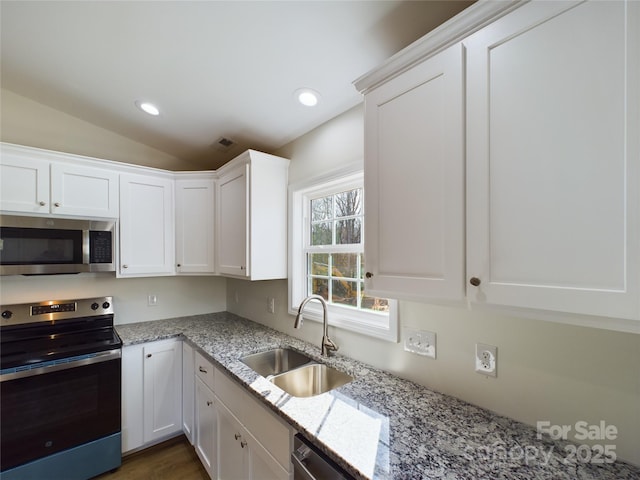 kitchen with lofted ceiling, white cabinets, sink, and stainless steel appliances