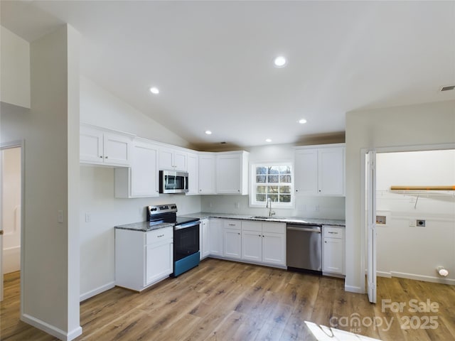 kitchen featuring white cabinets, lofted ceiling, stainless steel appliances, sink, and light hardwood / wood-style flooring