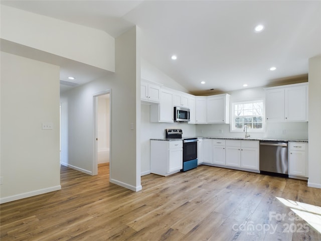 kitchen featuring white cabinetry, stainless steel appliances, light hardwood / wood-style floors, sink, and vaulted ceiling