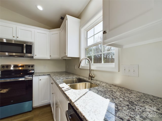 kitchen featuring vaulted ceiling, sink, white cabinetry, light stone countertops, and stainless steel appliances