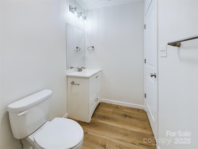 bathroom with toilet, wood-type flooring, and vanity