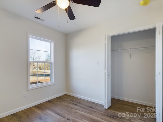 unfurnished bedroom featuring ceiling fan, hardwood / wood-style flooring, and a closet