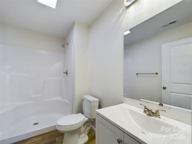 bathroom featuring toilet, vanity, a shower, and hardwood / wood-style flooring