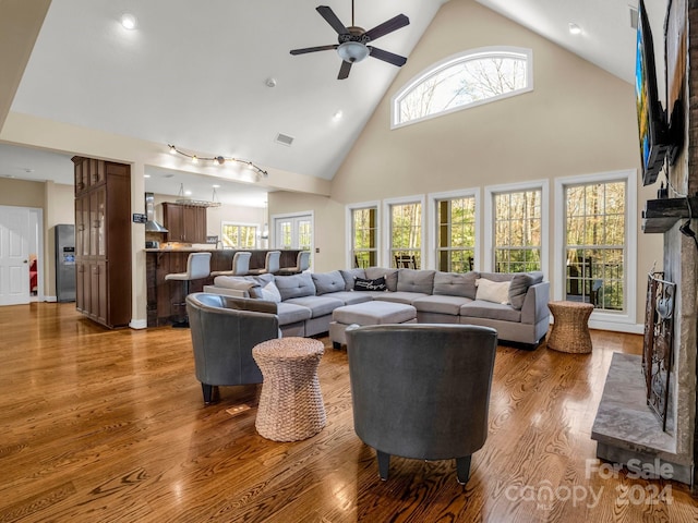 living room with ceiling fan, a healthy amount of sunlight, wood-type flooring, and high vaulted ceiling