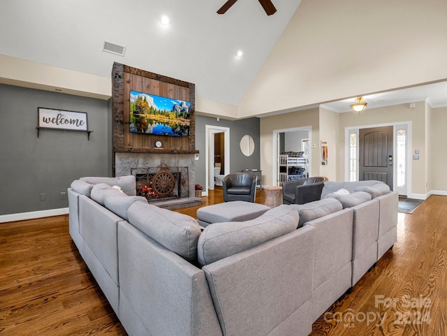 living room with a stone fireplace, ceiling fan, high vaulted ceiling, and hardwood / wood-style flooring