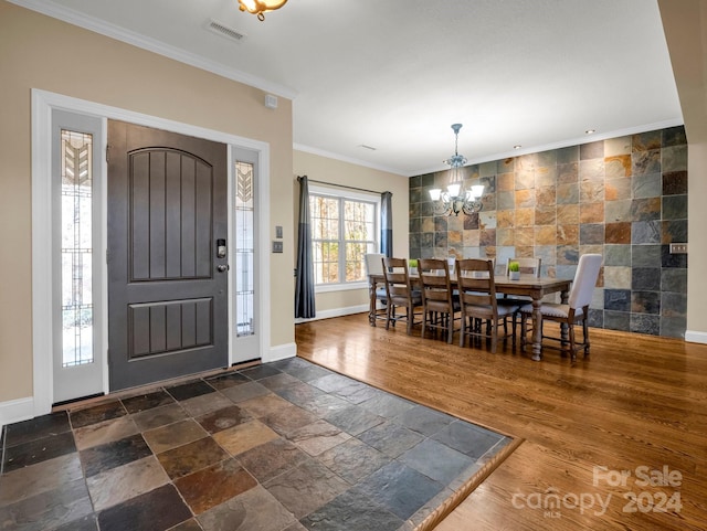 entryway featuring crown molding, dark hardwood / wood-style flooring, tile walls, and a notable chandelier