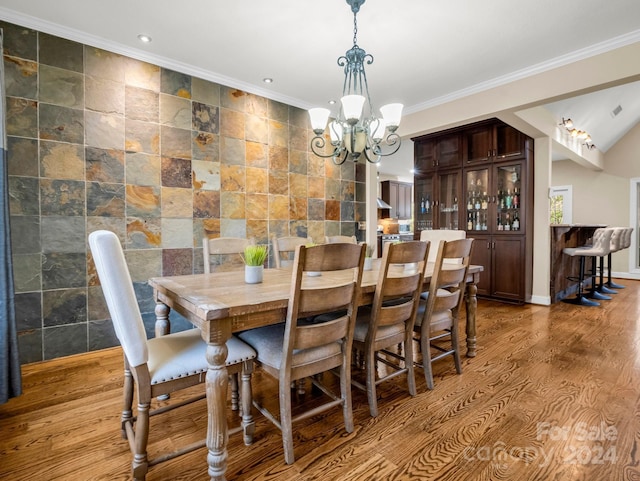 dining room with light hardwood / wood-style flooring, ornamental molding, tile walls, and a notable chandelier