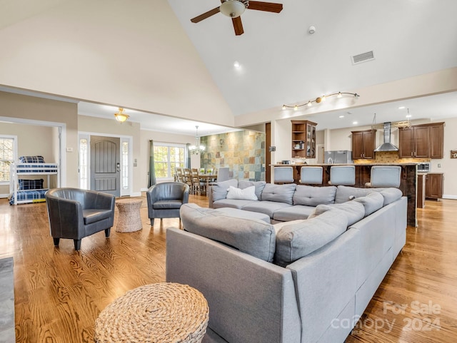 living room with light hardwood / wood-style flooring, high vaulted ceiling, and ceiling fan with notable chandelier