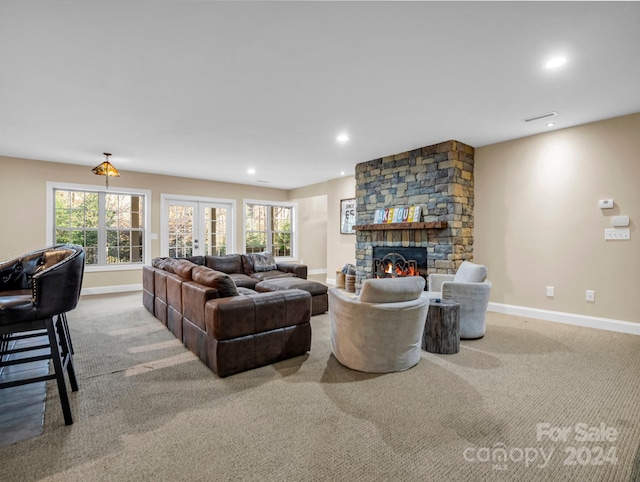 carpeted living room with a stone fireplace