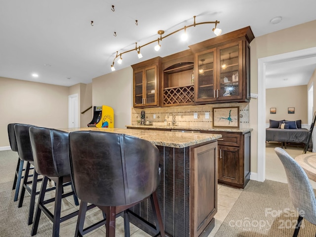 bar with light stone countertops, backsplash, and light tile patterned floors