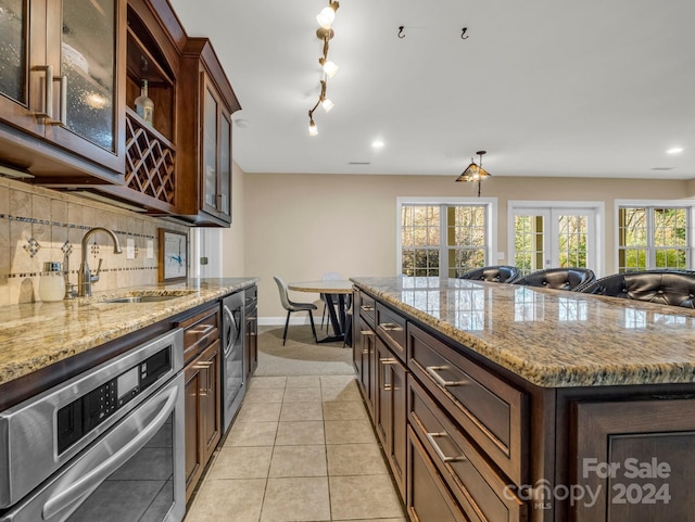 kitchen with stainless steel oven, sink, light tile patterned floors, tasteful backsplash, and a kitchen island