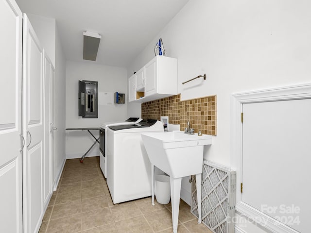 clothes washing area with washing machine and clothes dryer, electric panel, light tile patterned floors, and cabinets