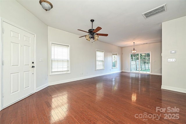 unfurnished living room with dark hardwood / wood-style floors, a healthy amount of sunlight, and ceiling fan with notable chandelier