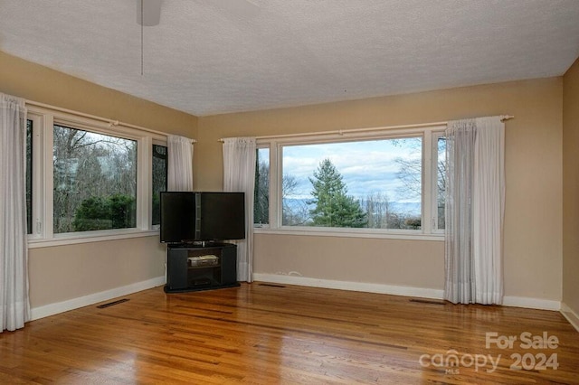 unfurnished living room with a textured ceiling, hardwood / wood-style flooring, and ceiling fan