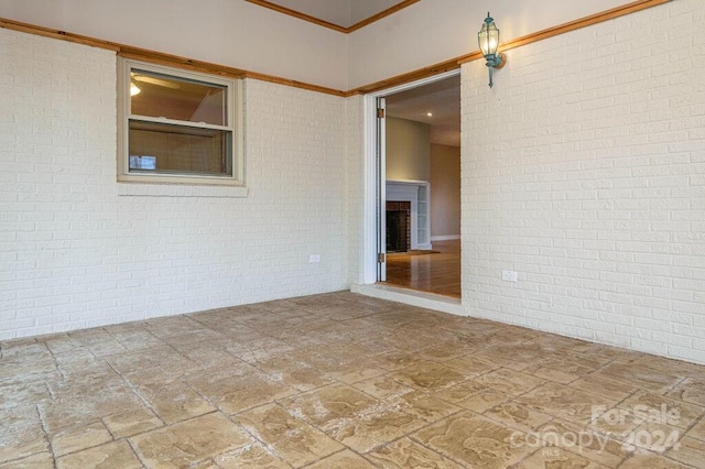 unfurnished room with brick wall and ornamental molding