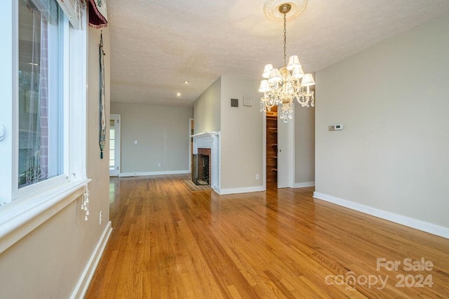 interior space featuring light hardwood / wood-style floors, a textured ceiling, and a chandelier