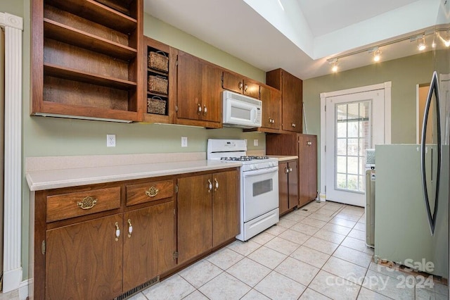 kitchen with lofted ceiling, white appliances, and light tile patterned floors