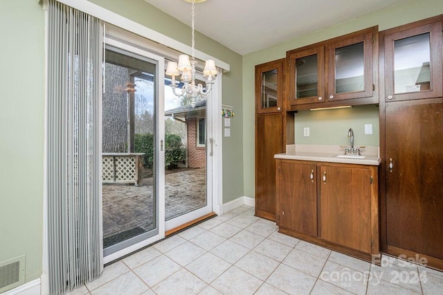 interior space with a chandelier, light tile patterned floors, decorative light fixtures, and sink