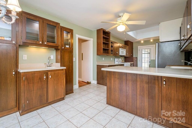 kitchen with ceiling fan, sink, kitchen peninsula, white appliances, and light tile patterned floors