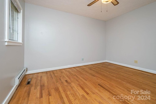 unfurnished room featuring a textured ceiling, light wood-type flooring, and baseboard heating