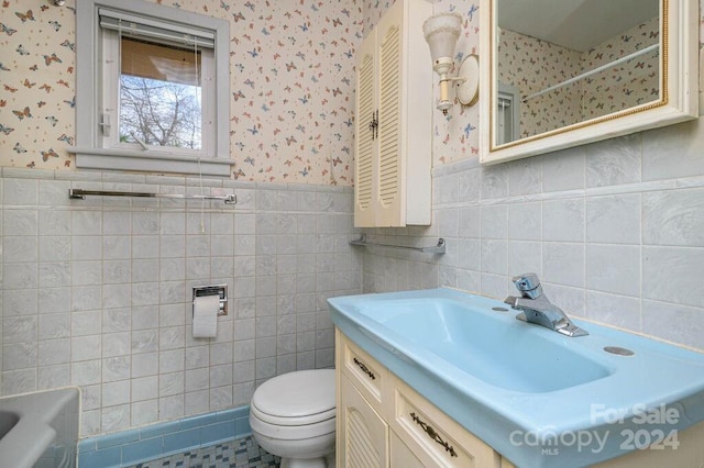 bathroom with vanity, toilet, and tile walls