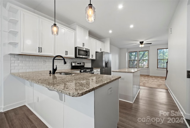 kitchen with appliances with stainless steel finishes, a kitchen island, sink, pendant lighting, and white cabinetry