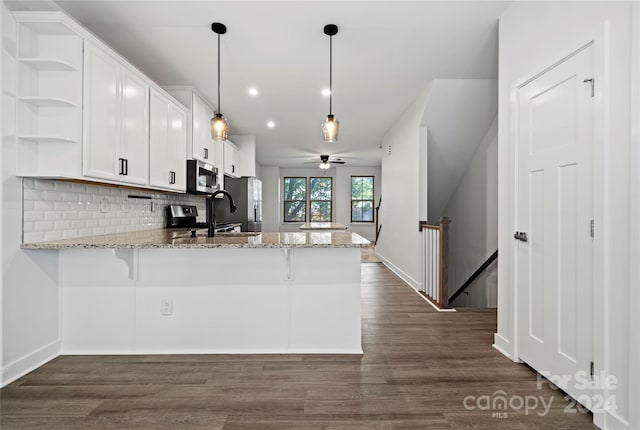 kitchen featuring kitchen peninsula, hanging light fixtures, dark hardwood / wood-style floors, white cabinetry, and stainless steel appliances