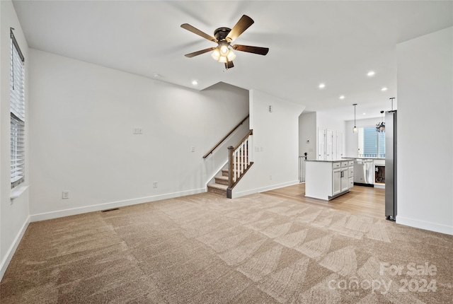 unfurnished living room with light carpet and ceiling fan