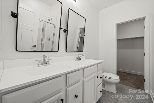 bathroom featuring toilet, vanity, tile patterned floors, and a shower with shower door