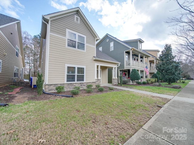 view of front facade with covered porch, a balcony, and a front yard