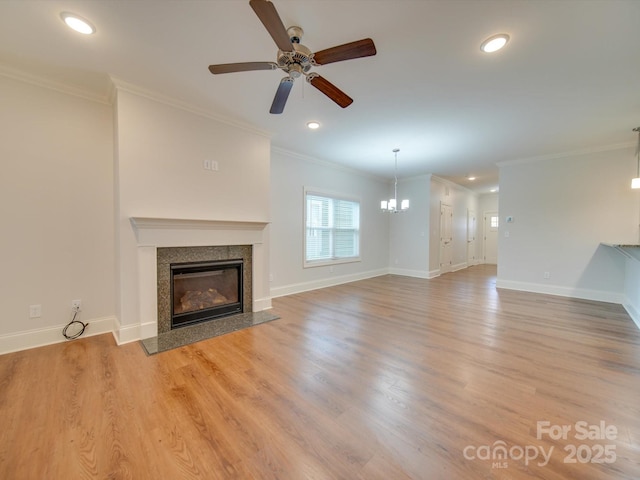 unfurnished living room with crown molding, a fireplace, light hardwood / wood-style floors, and ceiling fan with notable chandelier