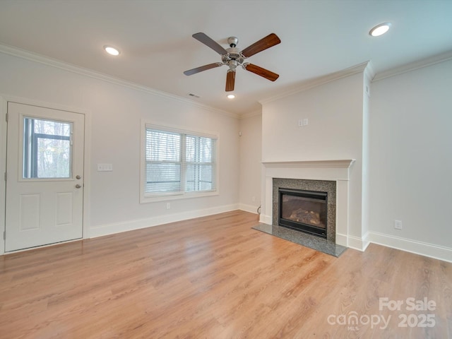 unfurnished living room featuring light wood-type flooring, ceiling fan, ornamental molding, and a premium fireplace