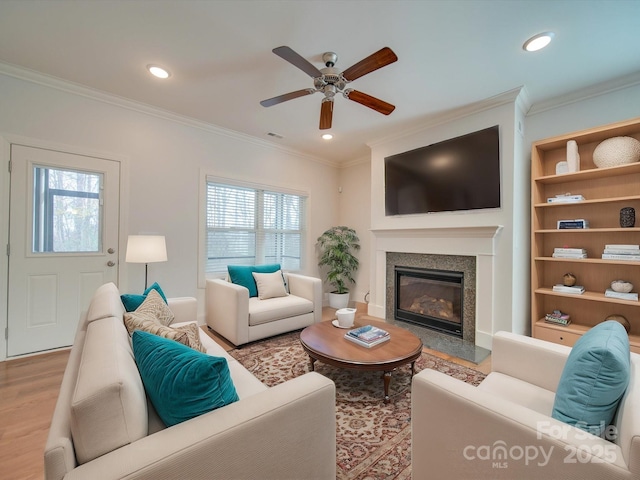 living room featuring light hardwood / wood-style flooring, a wealth of natural light, crown molding, and ceiling fan