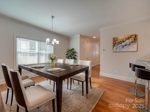 dining space featuring light hardwood / wood-style flooring, ornamental molding, and a notable chandelier