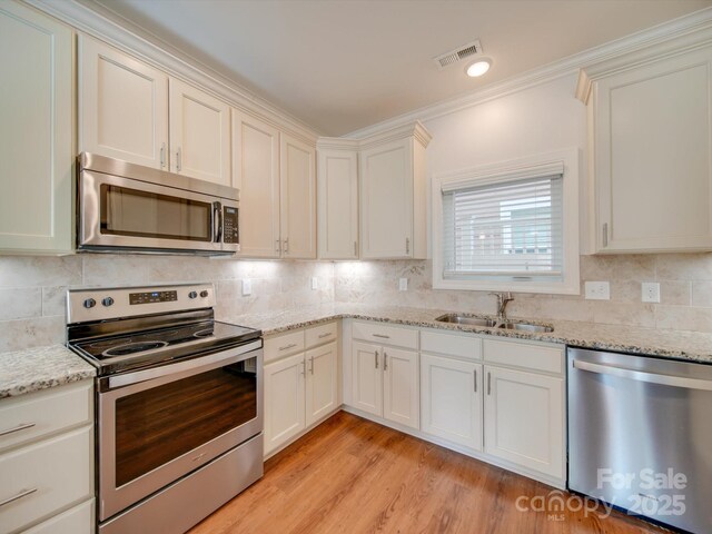 kitchen featuring backsplash, light stone counters, sink, and stainless steel appliances