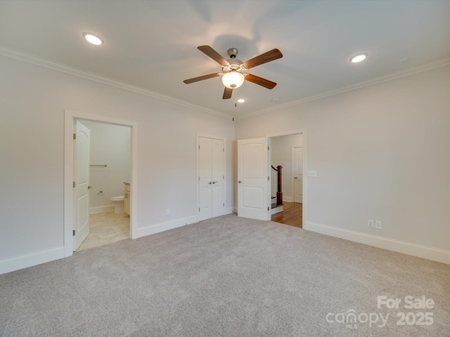 unfurnished bedroom featuring ceiling fan, light colored carpet, ornamental molding, and connected bathroom