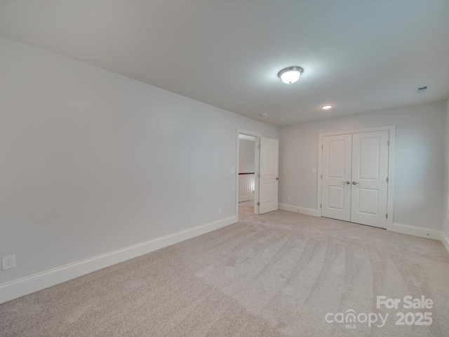 unfurnished bedroom with light carpet and a closet