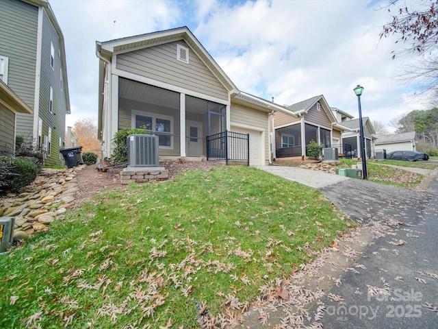 view of front of house with a front lawn, cooling unit, and a sunroom